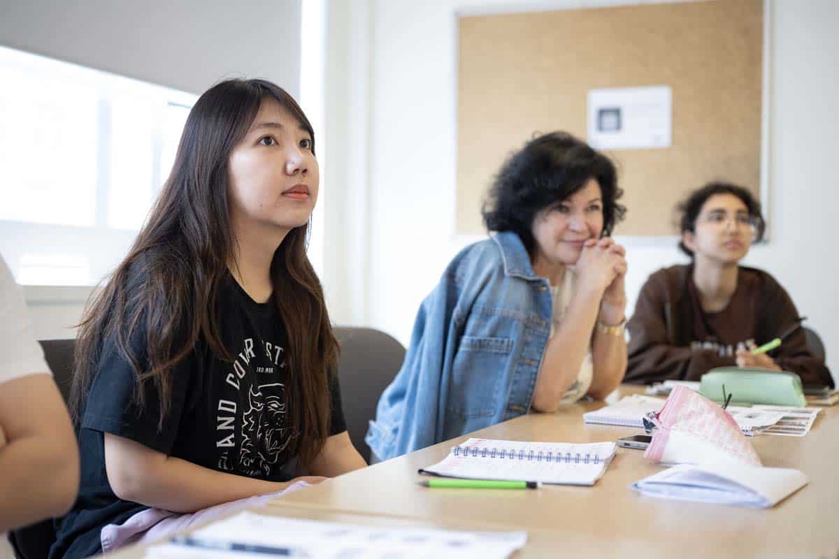 Studenten, die mit ihren Notizbüchern um einen Tisch im International House London sitzen