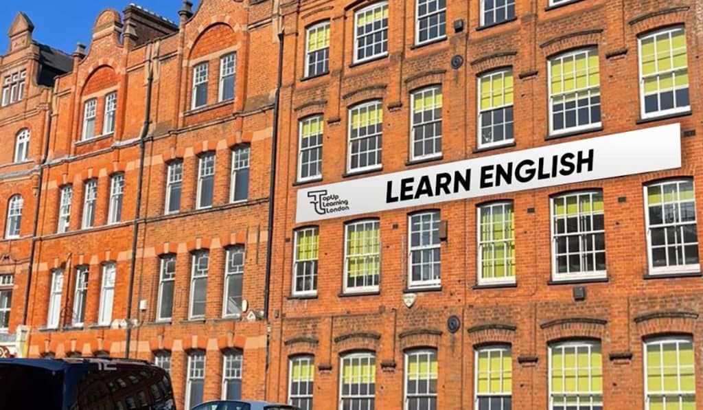 Prédio de tijolos vermelhos com um banner “Learn English” na Top Up Learning, em Londres