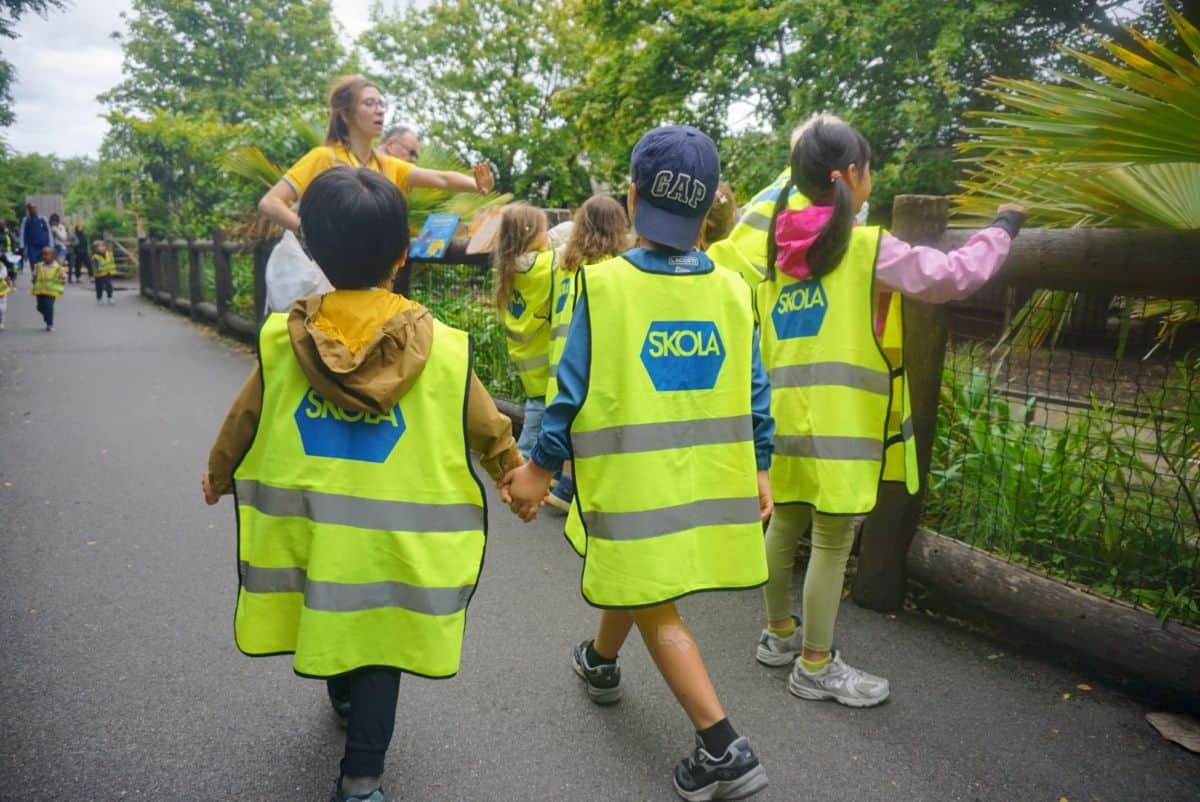 Unos jóvenes alumnos de Skola con chalecos reflectantes caminando por un sendero durante una excursión