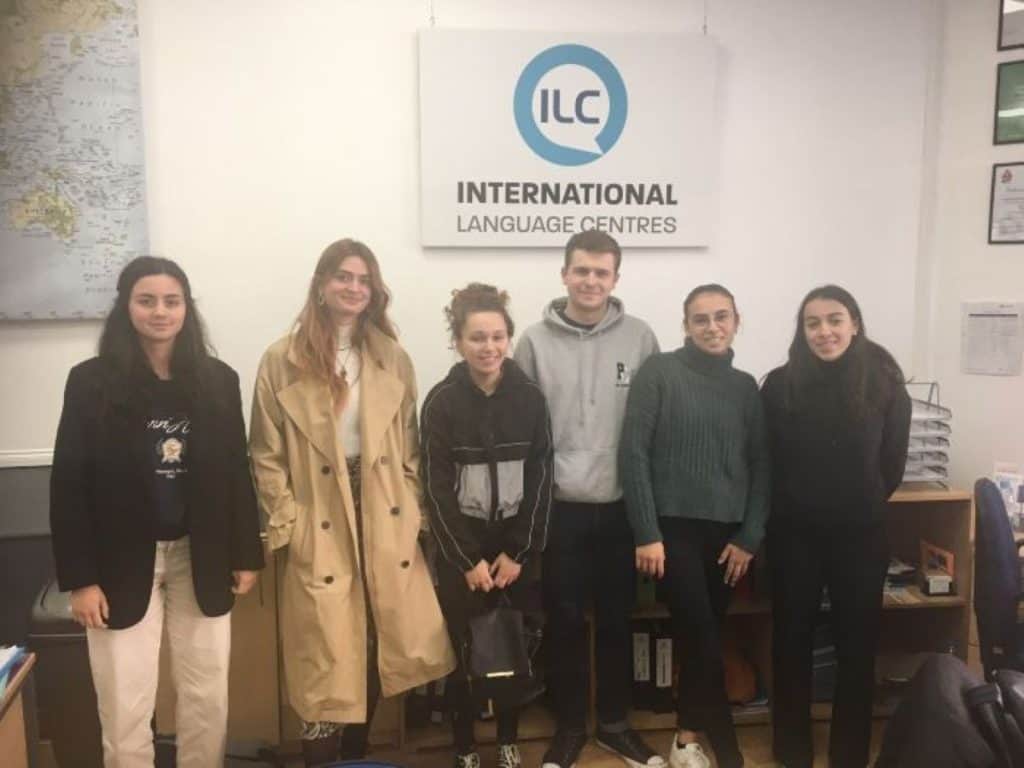 ポーツマスの「インターナショナル・ランゲージ・センターズ」の看板の下でポーズをとる6人の学生