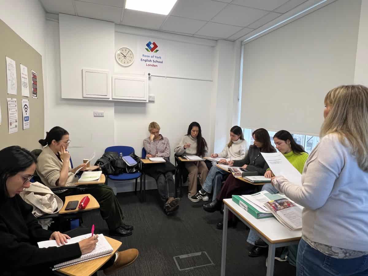 Un profesor repartiendo hojas de ejercicios a una clase en la escuela de inglés Rose of York