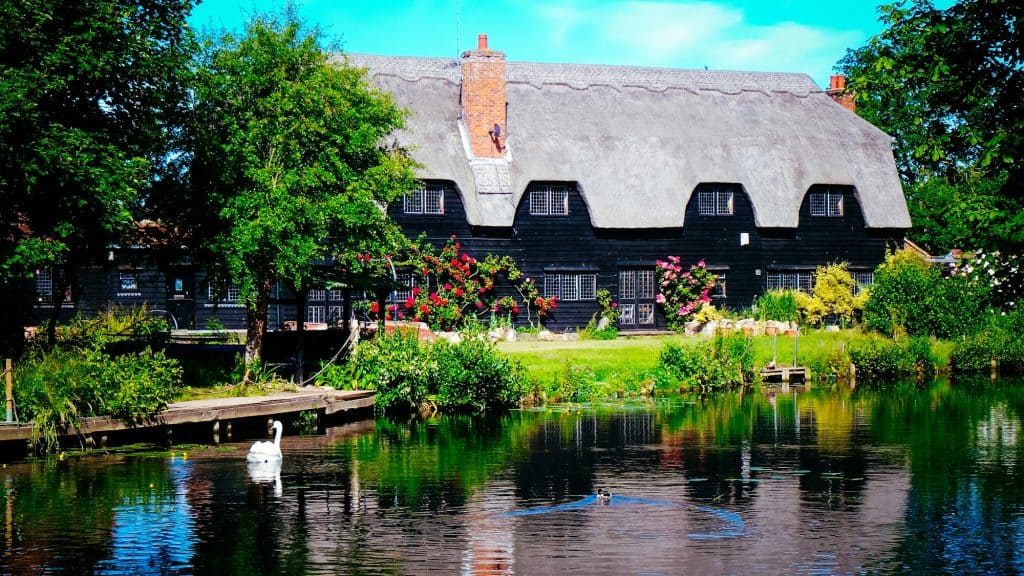Brown concrete building near green trees and river during daytime