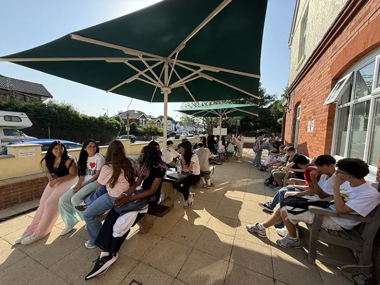 Schüler, die im sonnigen Vorgarten der Southbourne School of English sitzen